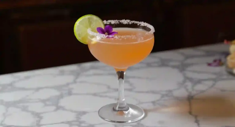 Strawberry daiquiri mocktail in a coupe glass with lime and edible flower garnish