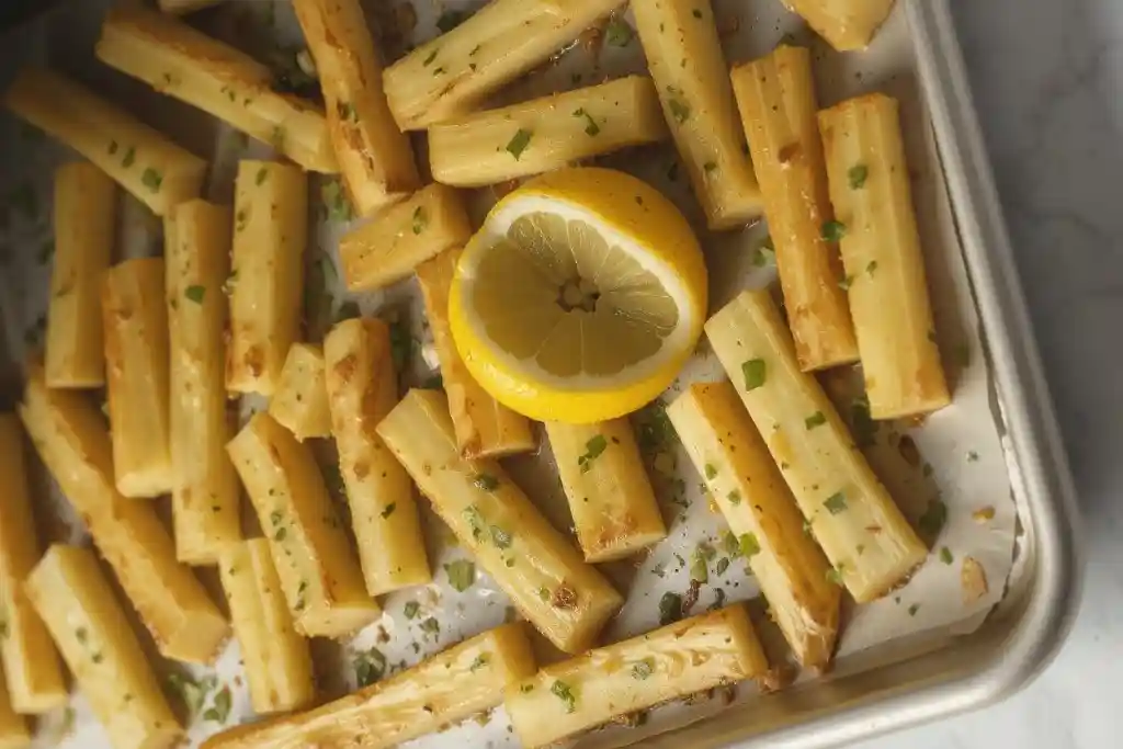 Golden roasted parsnips with herbs on white platter showing perfect caramelization