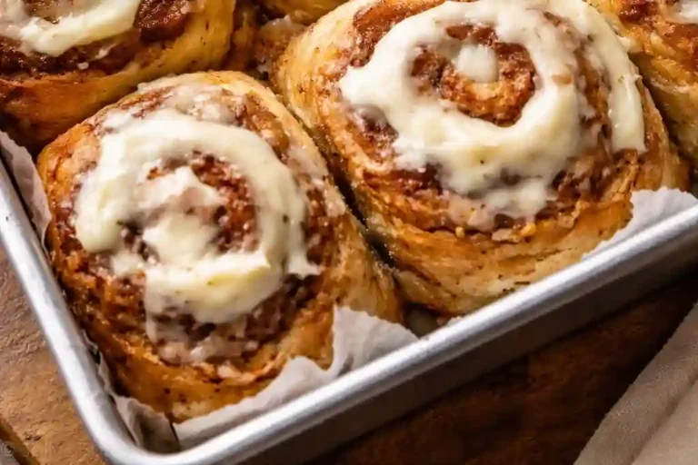 Freshly baked banana bread cinnamon rolls with cream cheese frosting in baking pan
