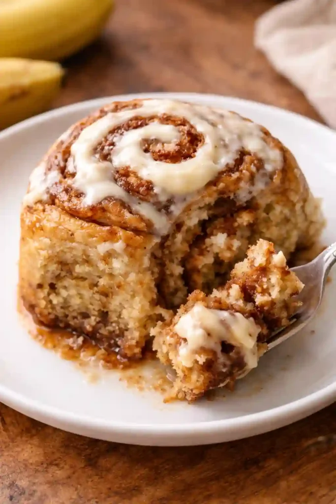 Single banana bread cinnamon roll showing cinnamon swirl layers on white plate